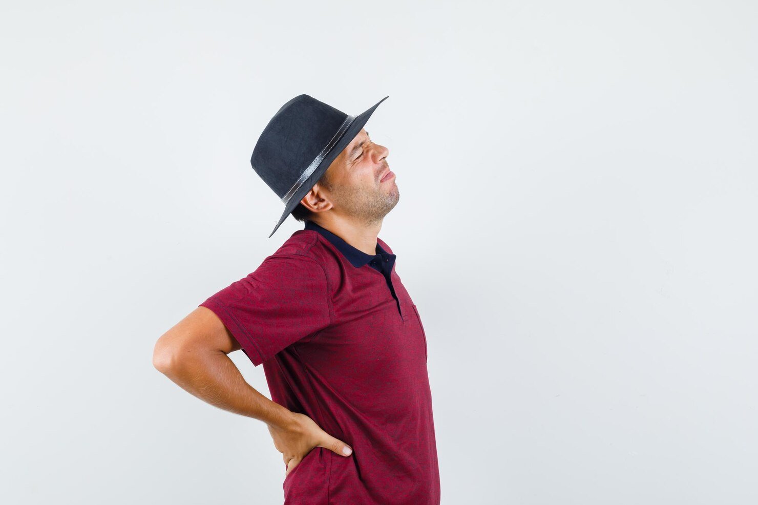 young-man-suffering-from-back-pain-t-shirt-hat-looking-tired_176474-93126